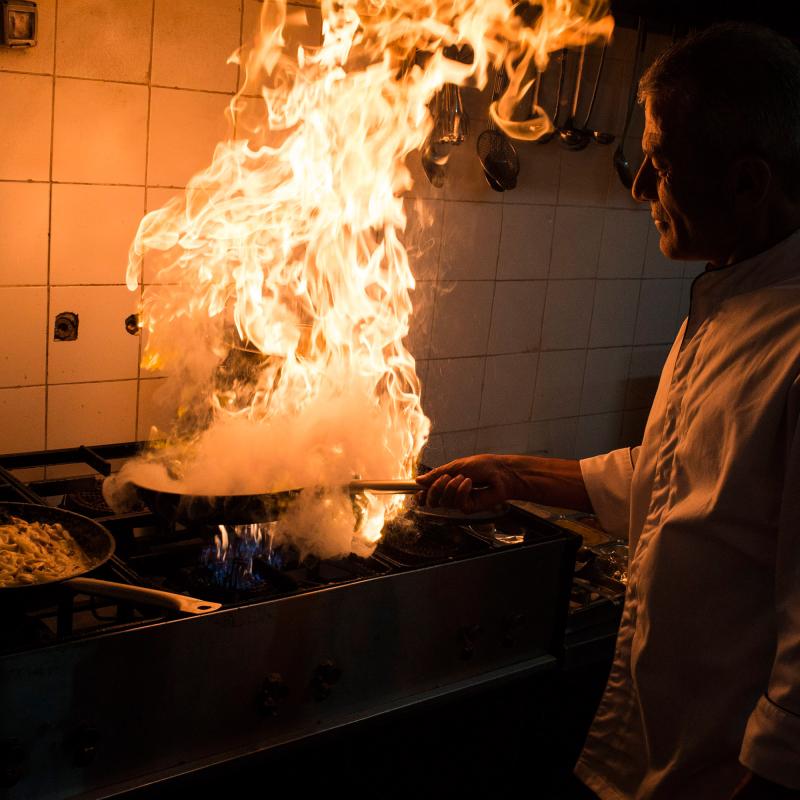 A Palestinian chef cooking with a large fire on a stovetop