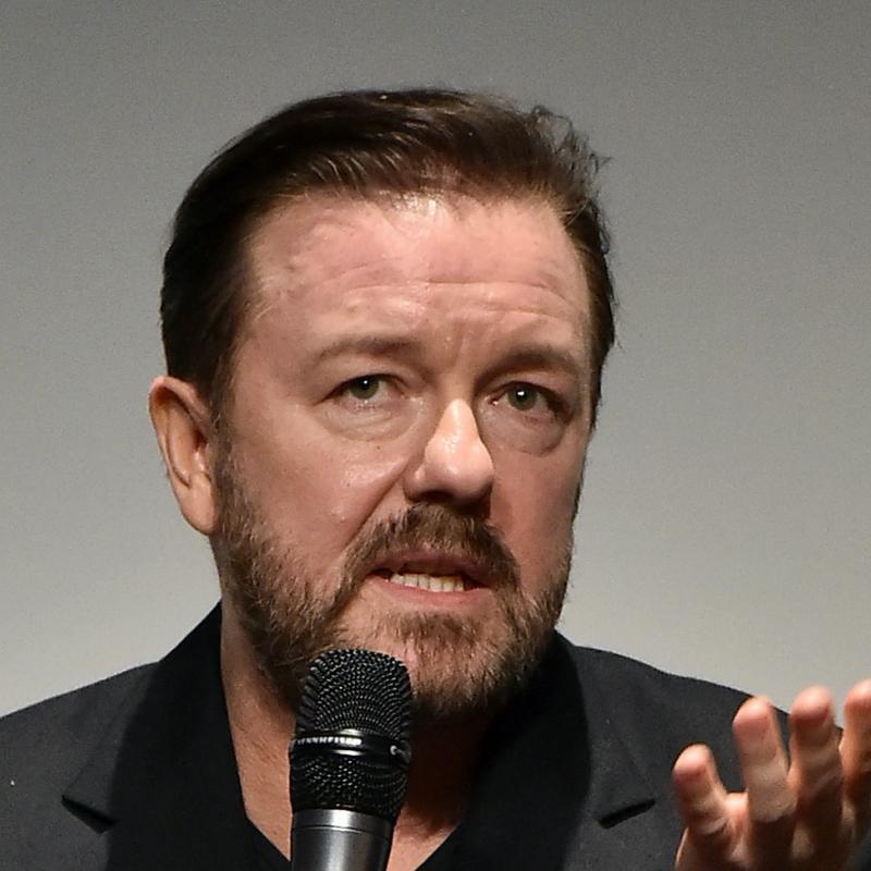 British comedian Ricky Gervais speaks in front of a microphone