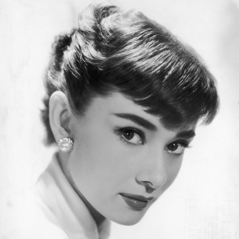 Audrey Hepburn looks into the camera in a black and white portrait
