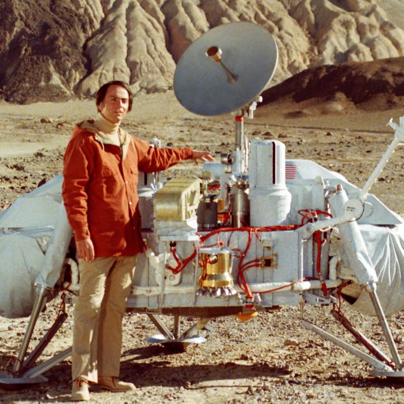 Scientist Carl Sagan poses next to a model of the Viking moon lander