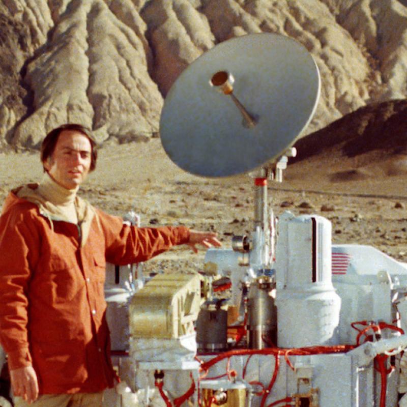 Scientist Carl Sagan poses next to a model of the Viking moon lander