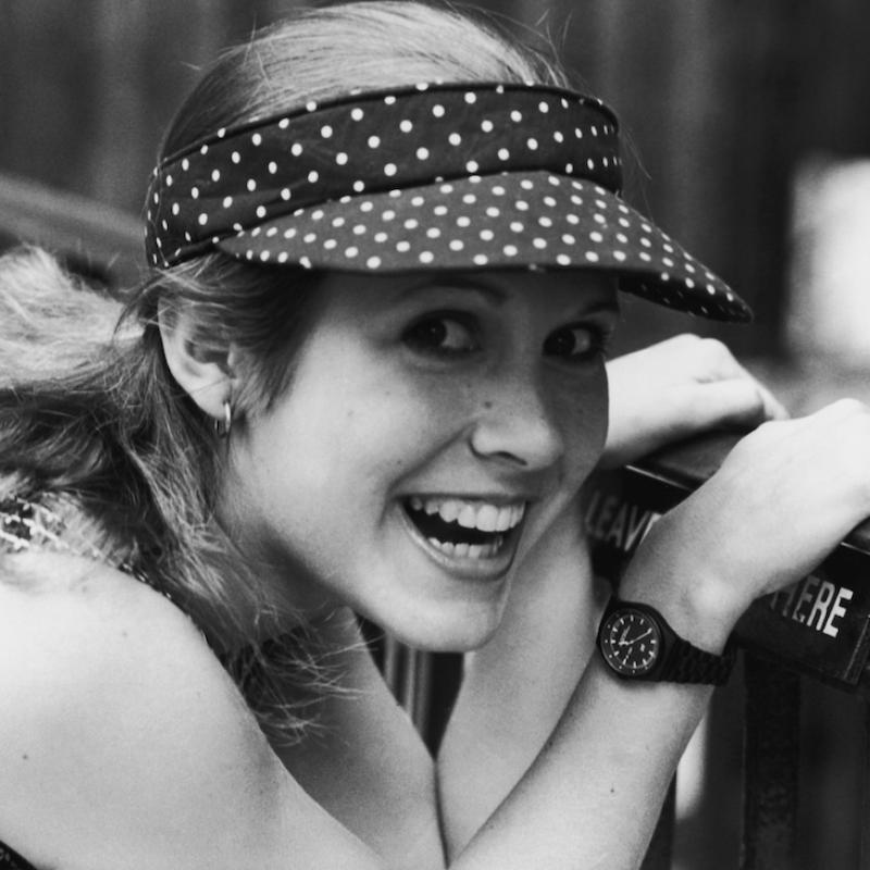 Actress Carrie Fisher smiles while holding onto a railing in this black and white photo from 1980