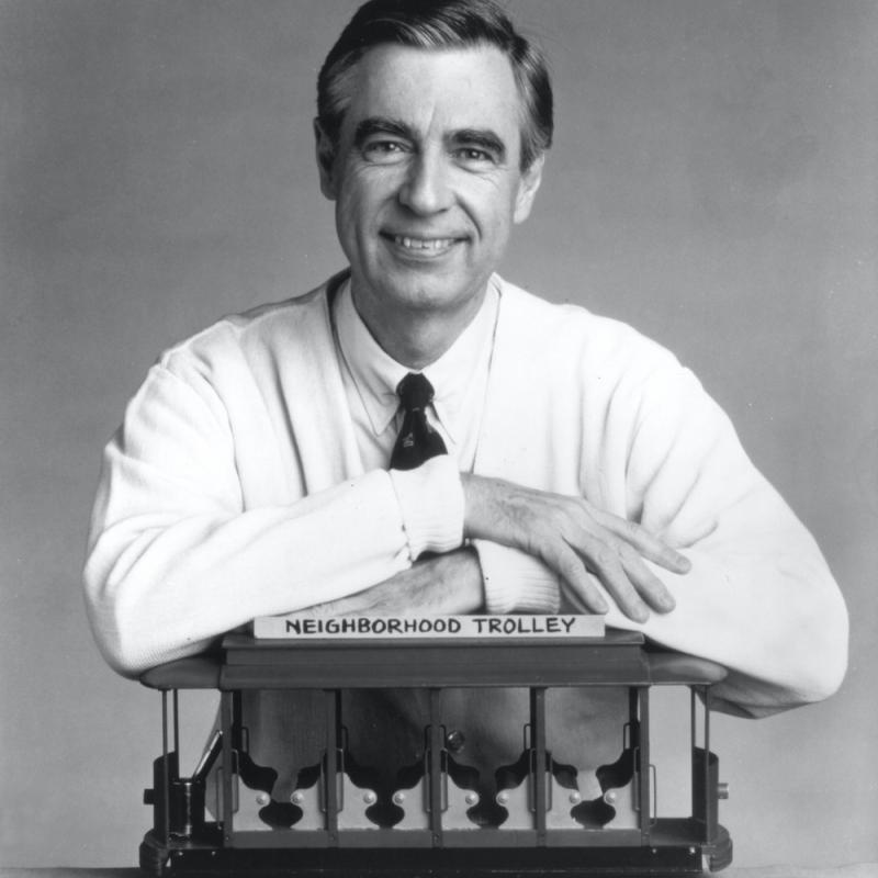 Fred Rogers, also known as Mister Rogers, posing with the Neighborhood Trolly from his show Mister Rogers Neighborhood