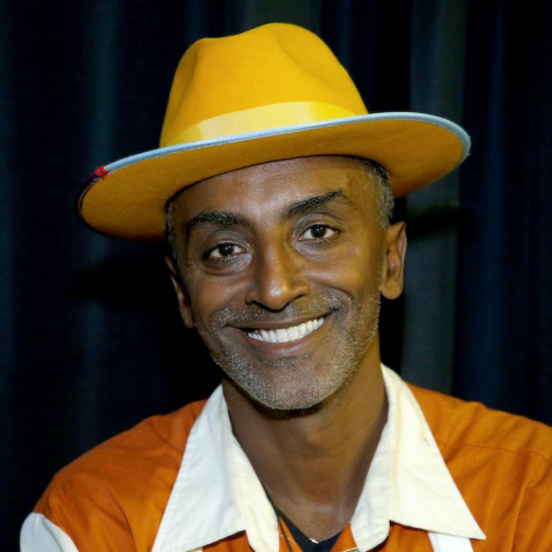 Chef and restauranteur Marcus Samuelsson smiles for the camera in a color outfit