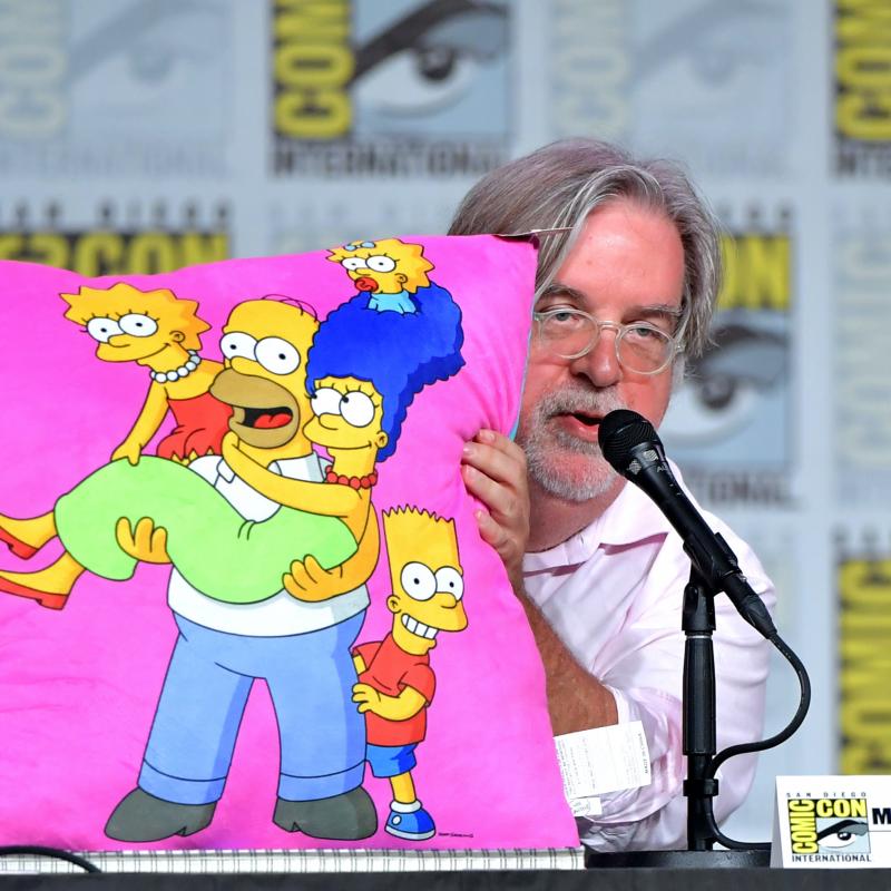 "The Simpsons" creator Matt Groening poses with a pillow showing the cartoon family at Comic Con
