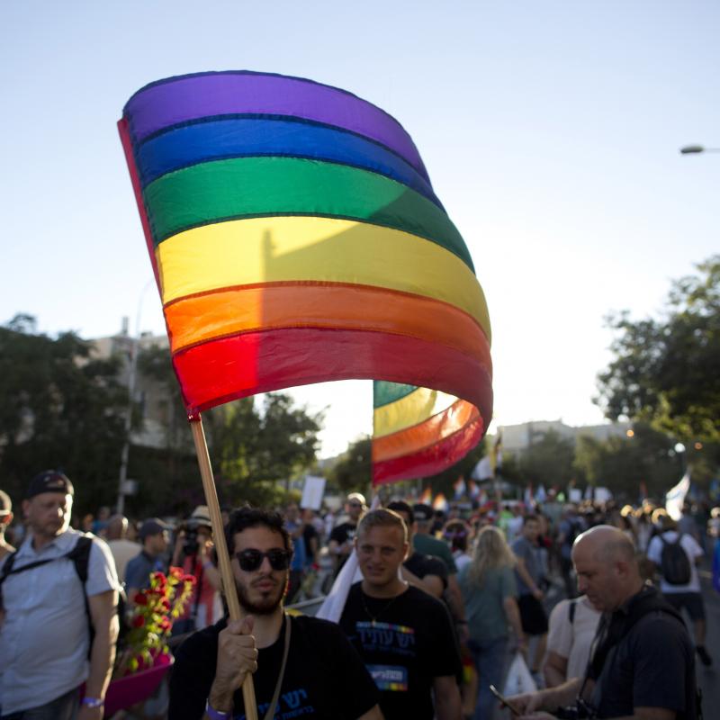 Israeli pride parade with a man waving the rainbow flag