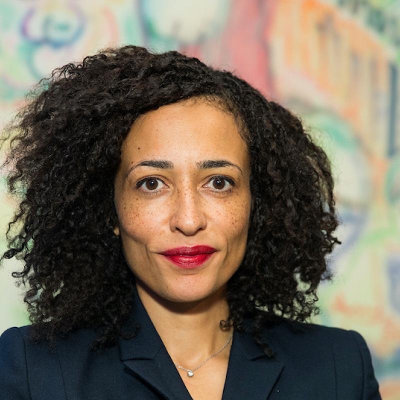 Writer Zadie Smith looks at the camera against a brightly colored backdrop