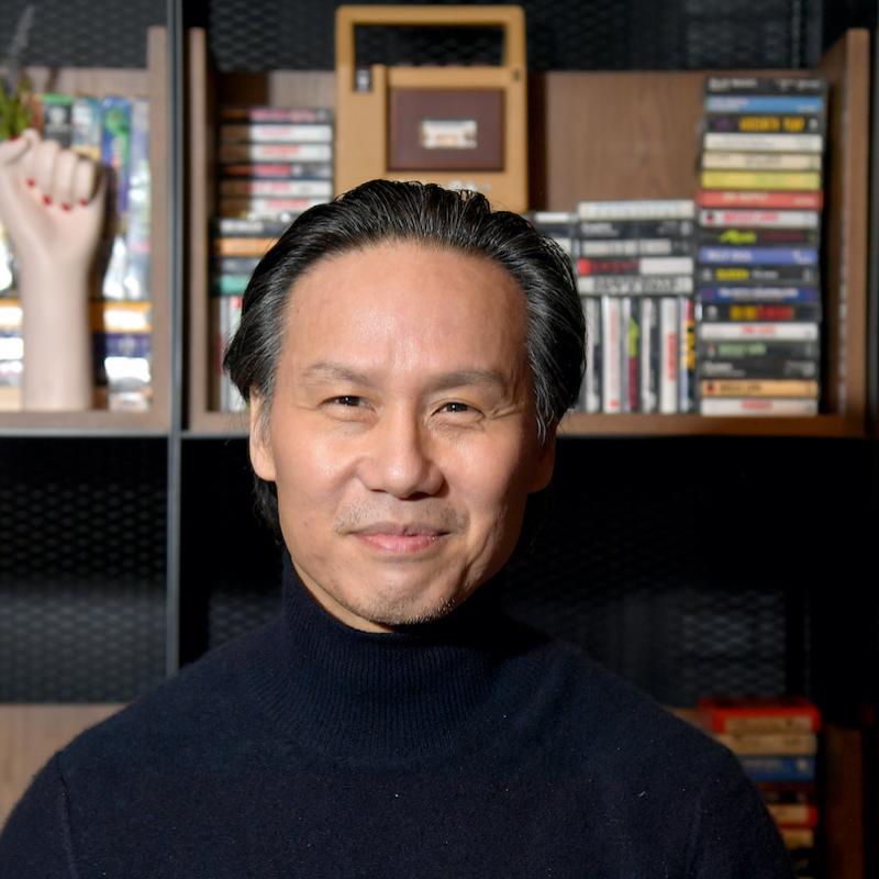 A portrait of actor B.D. Wong with a bookshelf behind him