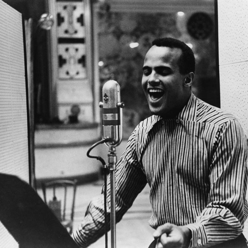 Black and white image of a young Harry Belafonte singing in a studio